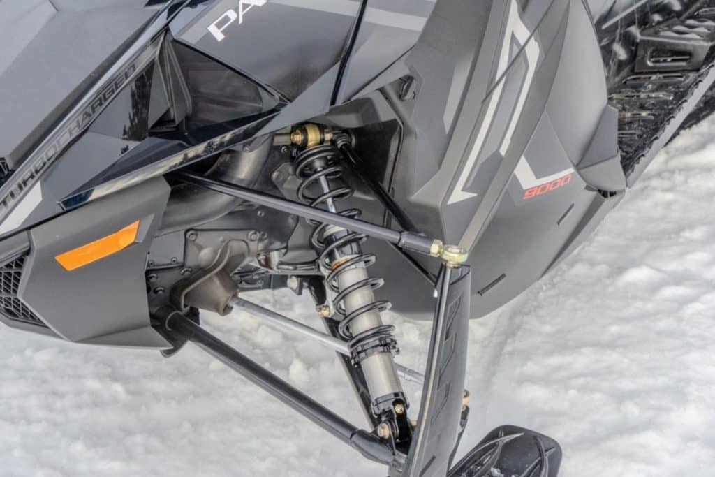 Vue rapprochée de la suspension avant et du ski d’une motoneige Arctic Cat Pantera 9000 Turbocharged, mettant en évidence les composants de direction et le design du carénage sur la neige.
